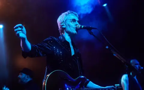 Cantante de Belako en concierto, con guitarra y micrófono, bajo luces azules y humo.