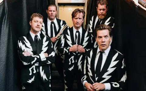 Los miembros de The Hives posan con trajes llamativos. Uno sostiene baquetas, listo para la acción.