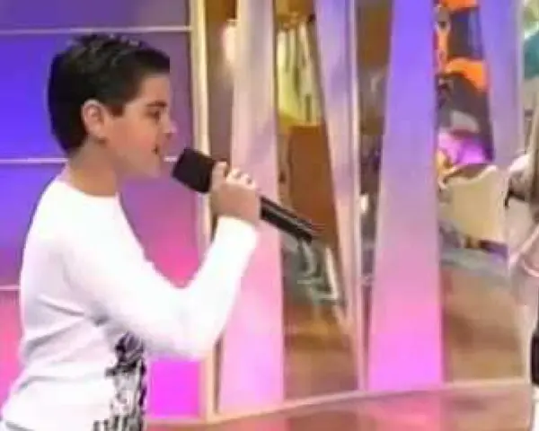 Ana Mena y Abraham Mateo, de niños, cantando con micrófonos en un escenario.