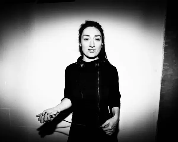 Paula Temple, DJ, con auriculares alrededor del cuello, sostiene cables de audio.