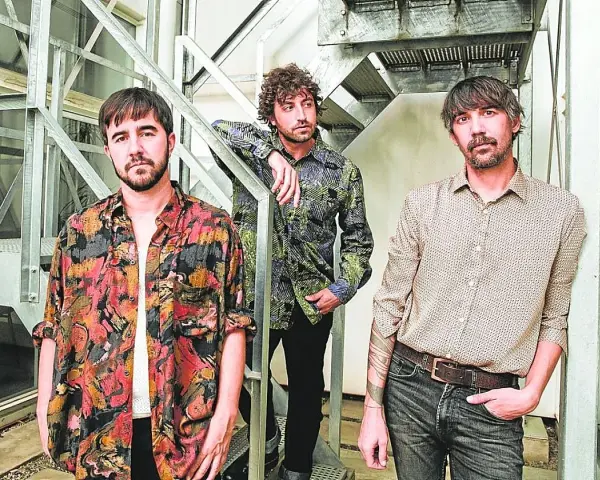 Los miembros de Lori Meyers posan juntos, con sus camisas estampadas y miradas serias, listos para su próxima actuación.