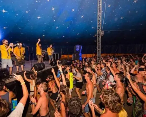 Una banda toca en un escenario ante una multitud animada bajo un techo estrellado.