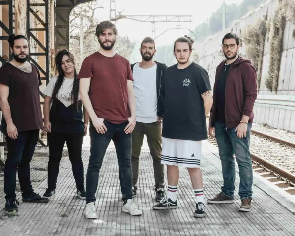 Los miembros de Itaca Band posan en una estación de tren abandonada, listos para su próxima aventura musical.