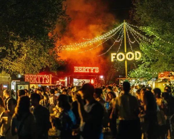 Noche de fiesta con luces de neón "Bertys" y "Food", gente disfrutando, ideal para canciones para un día ewan.