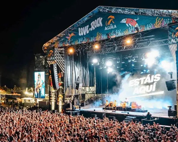 Multitud en concierto, luces brillantes y humo en el escenario. El cartel dice "Love to Rock".