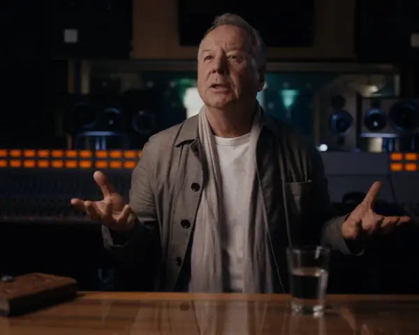 Jim Kerr, uno de los miembros de Simple Minds, habla en un estudio de grabación, con un libro y un vaso de agua sobre la mesa.