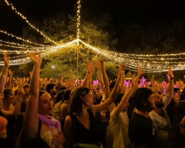 Gente disfrutando en el festival Ewan Salinas bajo un cielo de luces.