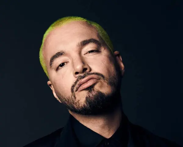 J Balvin, con su característico cabello verde vibrante, posa con una mirada intensa. Podría estar preparándose para un concierto en Madrid.