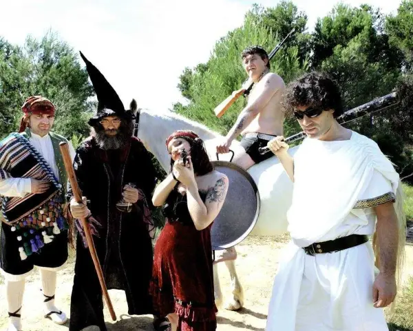 Un grupo peculiar, con atuendos que evocan a "wau y los arrrghs", posa con armas y un caballo blanco.