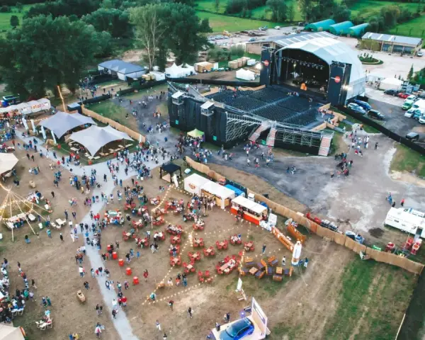 Vista aérea de un festival al aire libre con un gran escenario, carpas, puestos de comida y mucha gente disfrutando del summerfest Cerdanya.