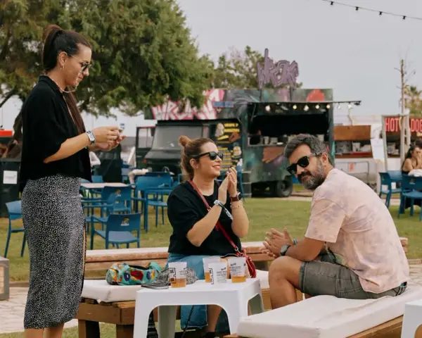 Amigos disfrutan del ambiente de rock en Valencia, con food trucks y música de fondo.