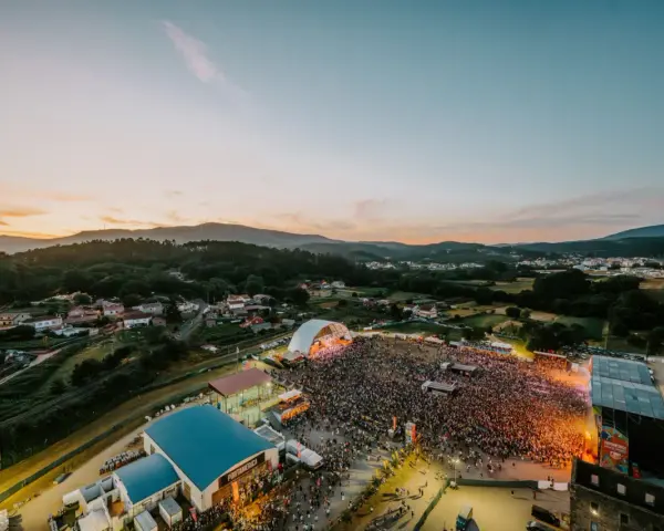 Multitudinaria **rio verbena fest** bajo un atardecer espectacular. Miles de personas disfrutan de la música y el ambiente.