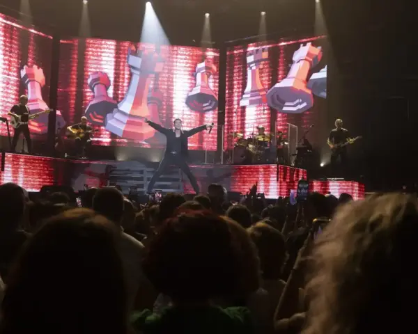 Un cantante en el escenario del 101 music festival, con una pantalla gigante de ajedrez de fondo.