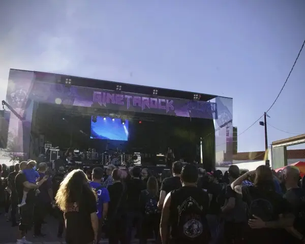 Multitud disfrutando del concierto de gineta rock bajo un cielo azul.