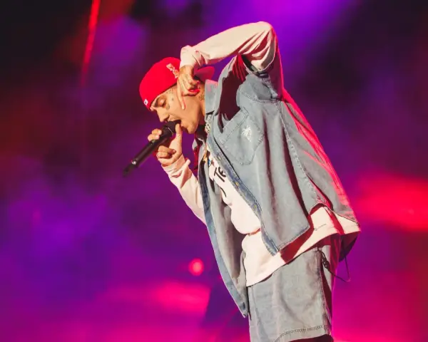 Un artista con gorra roja y ropa vaquera canta en un concierto boombastic Asturias.