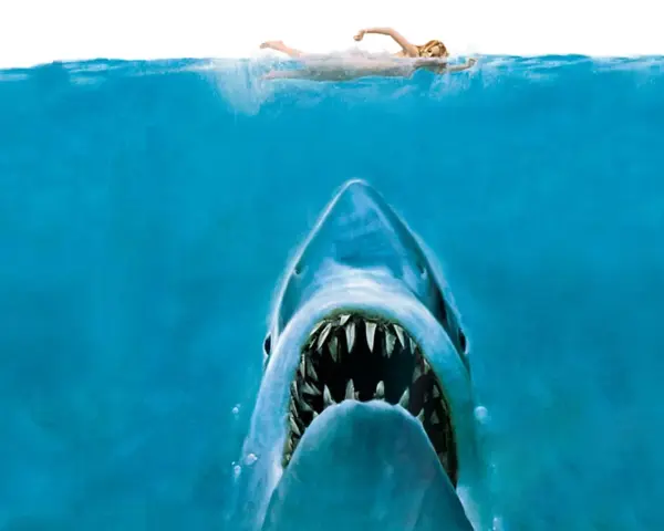 Un tiburón emerge de las profundidades, con la boca abierta, mientras una nadadora se acerca a la superficie. La icónica banda sonora de tiburón resuena.