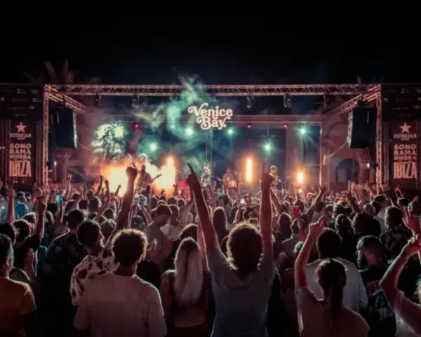 Multitud en concierto bajo luces y humo, con cartel de "Venice Bay" y "Sonorama Ibiza".