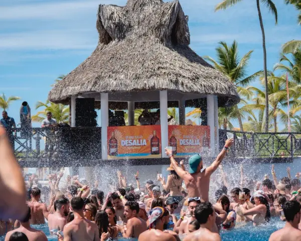 Gente disfrutando en una piscina con un escenario de Barceló Desalia al fondo.