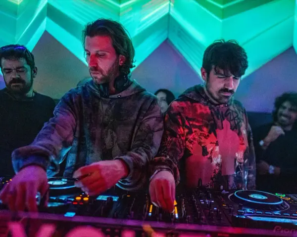 Los agentes del tiempo, DJs concentrados, manipulan las consolas bajo luces de neón, creando ritmos que desafían el tiempo.