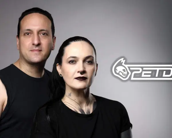 Un hombre y una mujer con tatuajes posan juntos. El logo de PETDUO aparece a la derecha.