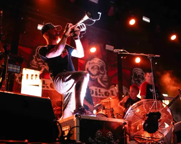 Músico con trompeta en un concierto de soria rock, con luces rojas y fondo de calaveras.