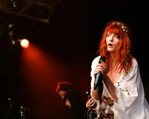 Florence Welch, una de los miembros de Florence and the Machine, canta con pasión en el escenario, iluminada por una luz roja.
