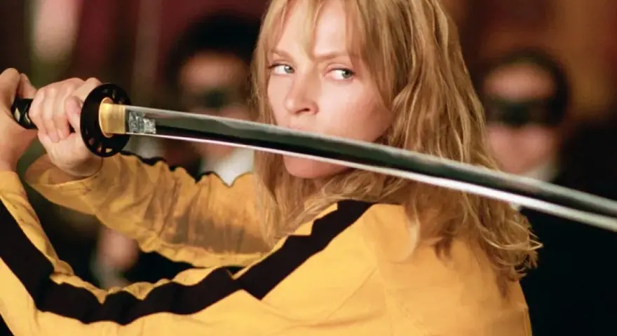 La Novia, con su icónico traje amarillo, desenvaina su katana. La banda sonora de Kill Bill resuena en esta escena de acción.