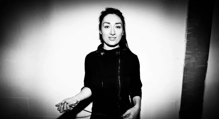 Paula Temple, DJ, con auriculares alrededor del cuello, sostiene cables de audio.