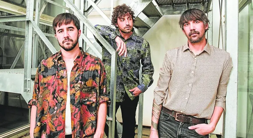 Los miembros de Lori Meyers posan juntos, con sus camisas estampadas y miradas serias, listos para su próxima actuación.