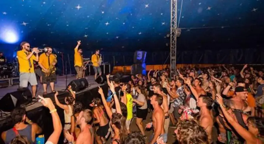 Una banda toca en un escenario ante una multitud animada bajo un techo estrellado.