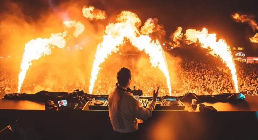 DJ enciende la fiesta en una **nova era beach party** con llamas y una multitud eufórica.