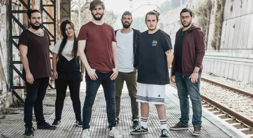 Los miembros de Itaca Band posan en una estación de tren abandonada, listos para su próxima aventura musical.