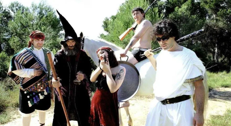 Un grupo peculiar, con atuendos que evocan a "wau y los arrrghs", posa con armas y un caballo blanco.