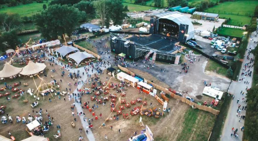 Vista aérea de un festival al aire libre con un gran escenario, carpas, puestos de comida y mucha gente disfrutando del summerfest Cerdanya.