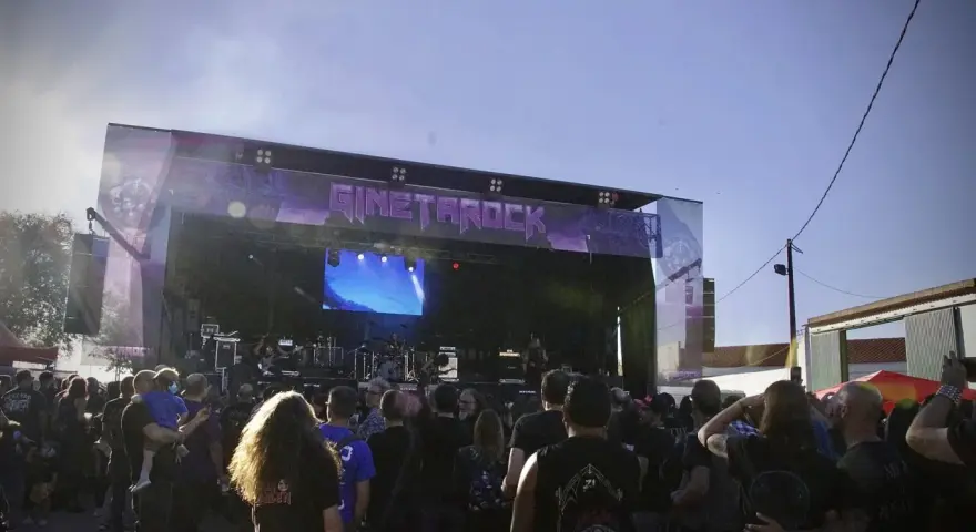 Multitud disfrutando del concierto de gineta rock bajo un cielo azul.