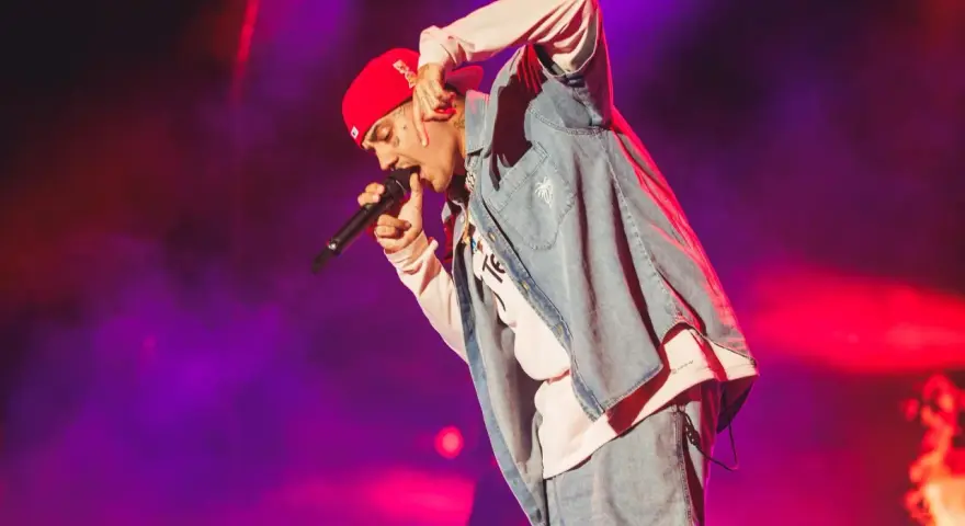 Un artista con gorra roja y ropa vaquera canta en un concierto boombastic Asturias.