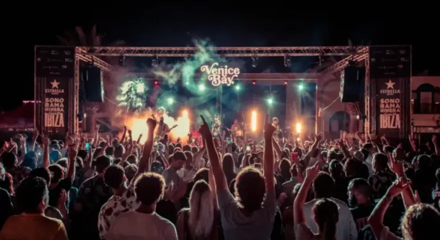 Multitud en concierto bajo luces y humo, con cartel de "Venice Bay" y "Sonorama Ibiza".