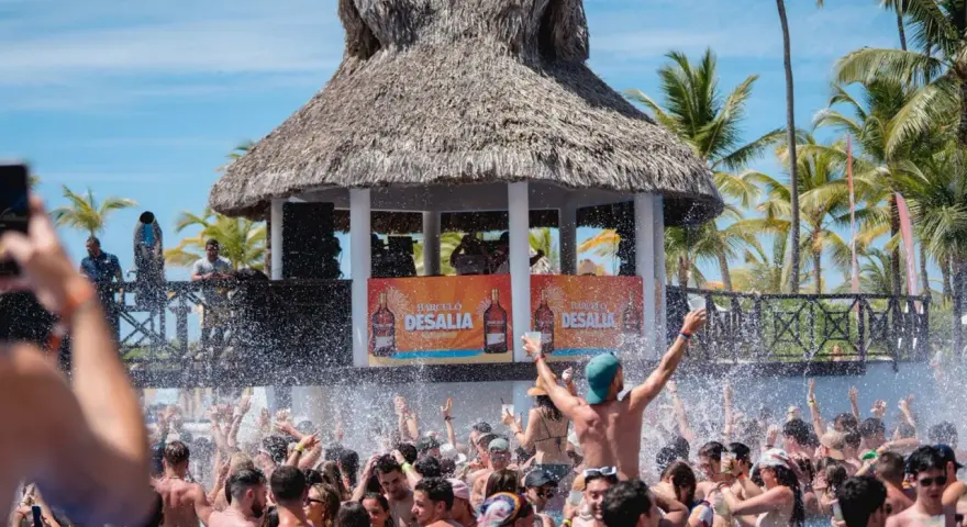Gente disfrutando en una piscina con un escenario de Barceló Desalia al fondo.