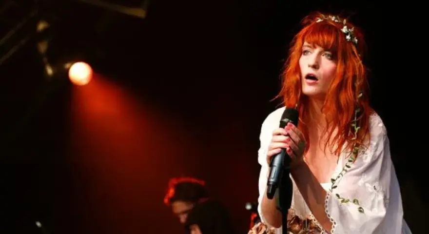 Florence Welch, una de los miembros de Florence and the Machine, canta con pasión en el escenario, iluminada por una luz roja.