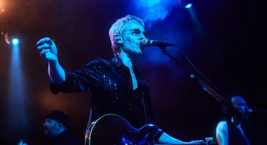 Cantante de Belako en concierto, con guitarra y micrófono, bajo luces azules y humo.
