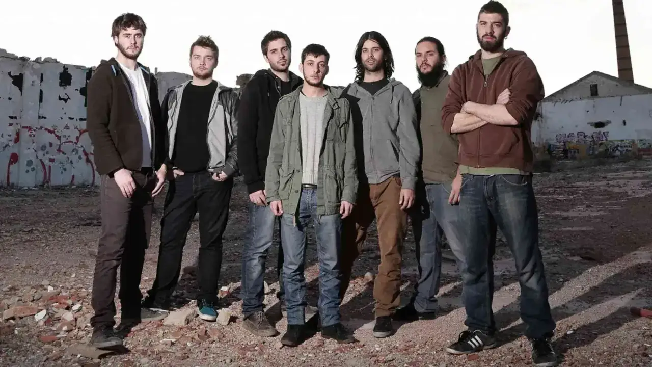 Los miembros de Itaca Band posan en un entorno urbano abandonado, con grafitis y escombros.