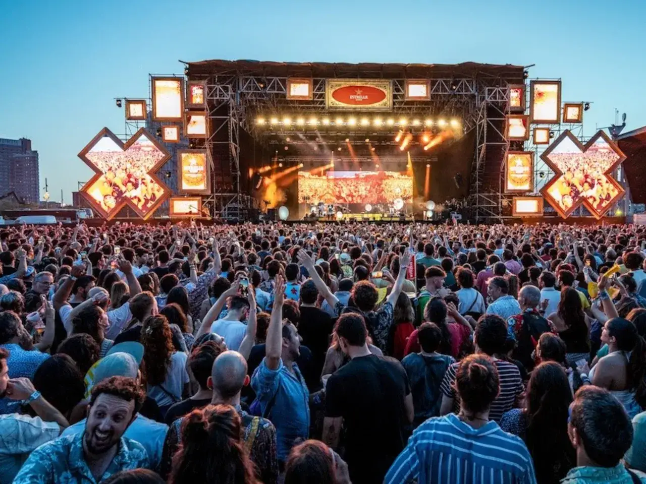 Multitud vibrante en conciertos de julio, disfrutando de la música bajo un cielo azul.