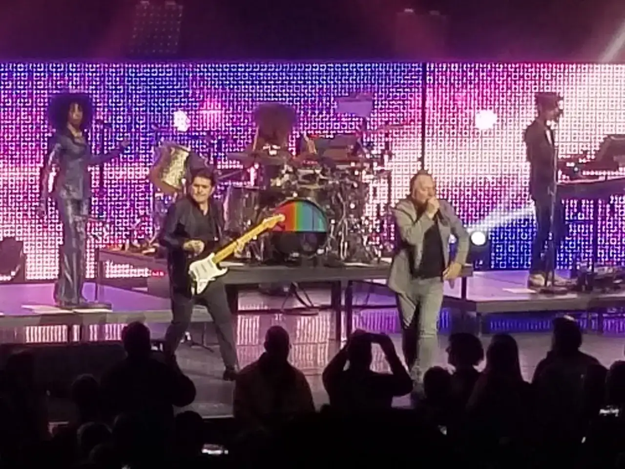 Miembros de Simple Minds en concierto, con Jim Kerr cantando y Charlie Burchill tocando la guitarra.