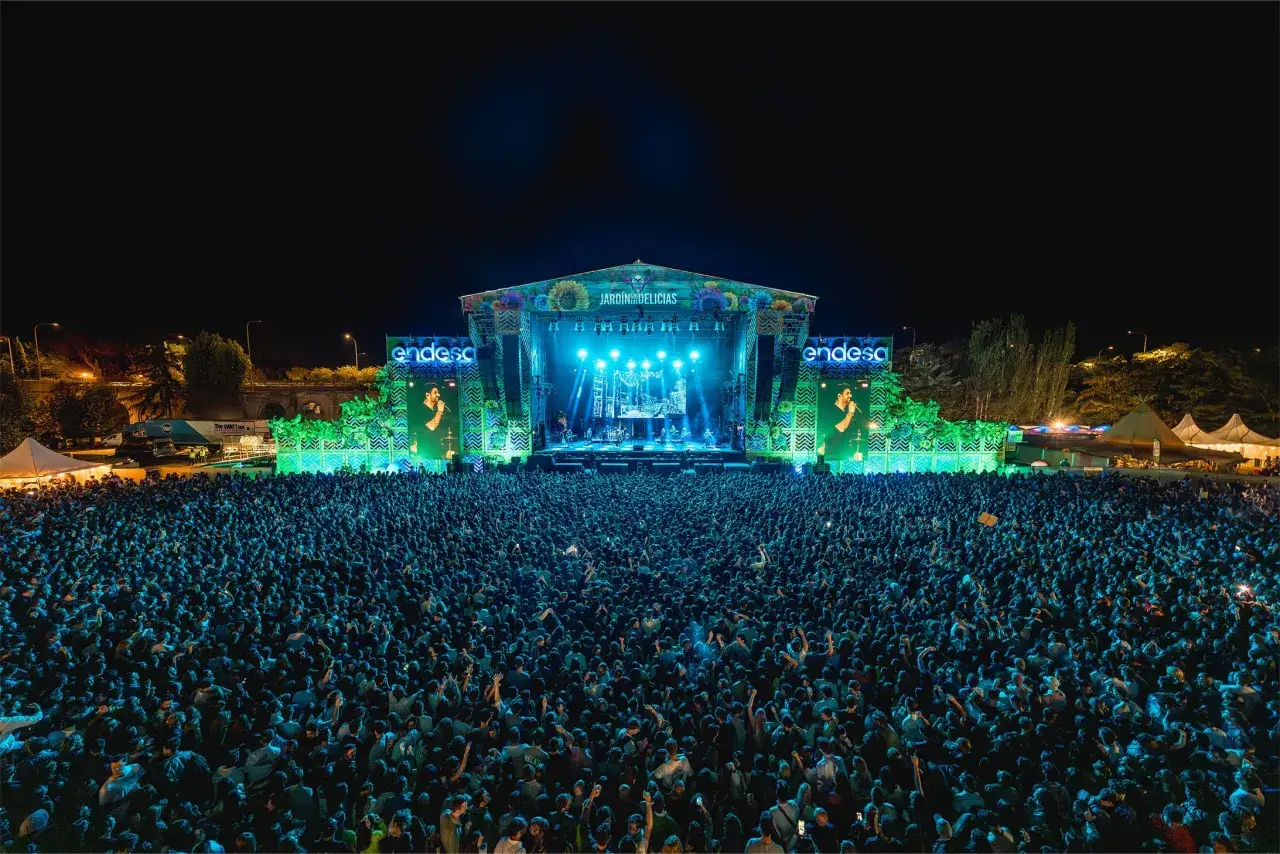 Gran concierto en el Jardín de las Delicias. Multitud disfrutando bajo un escenario iluminado.