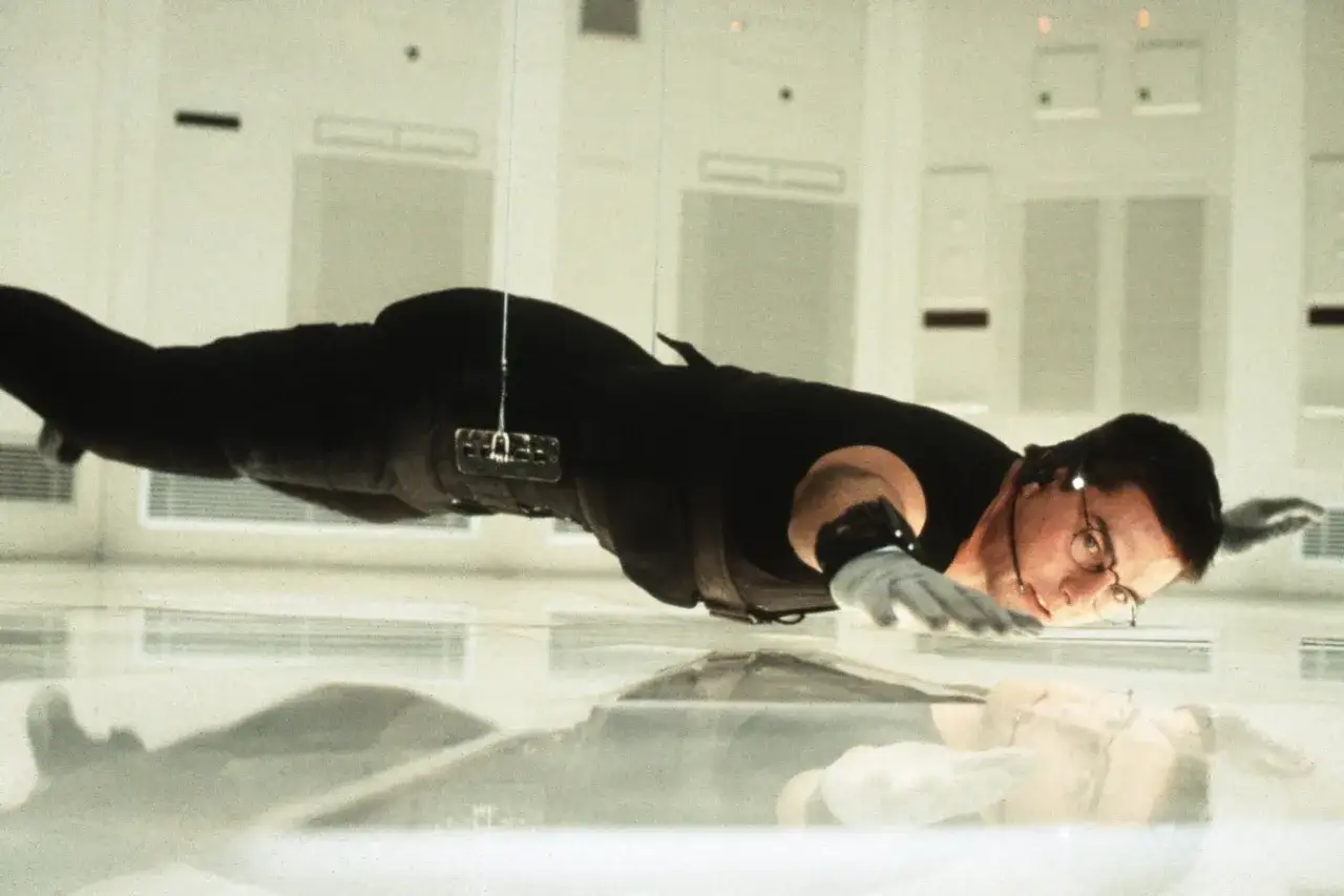 Ethan Hunt, en una bso misión imposible, flota en el aire, suspendido por cables, con un reflejo en el suelo.