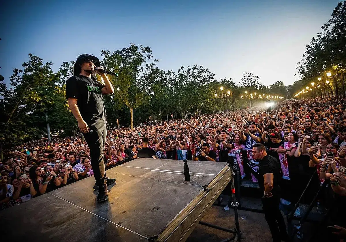 Un artista canta ante una multitud en un concierto al aire libre. La dellafuente biografia se escribe con cada actuación.