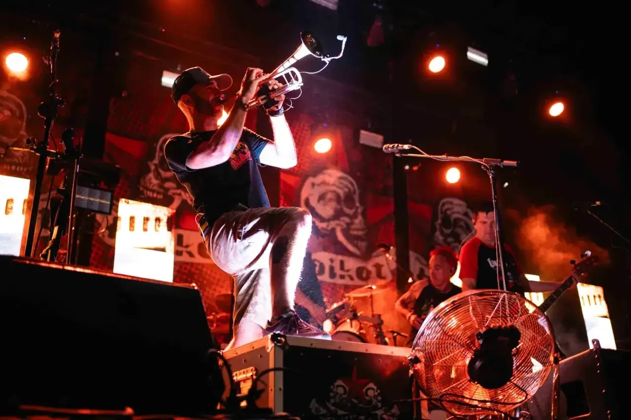 Músico con trompeta en un concierto de soria rock, con luces rojas y fondo de calaveras.