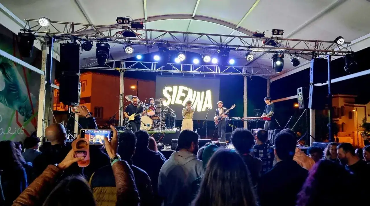 Una banda toca en un escenario iluminado, con el nombre