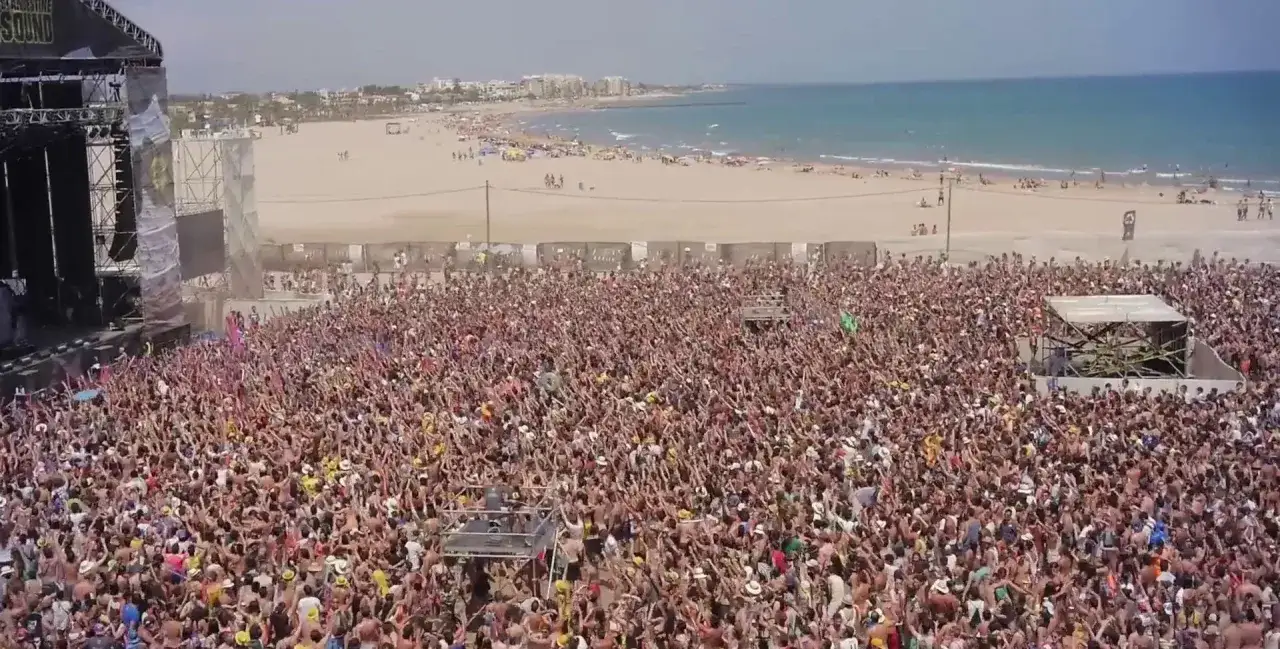 Multitud enloquecida en el Arenal Sound Valencia, con el mar y la playa de fondo. ¡Pura energía!