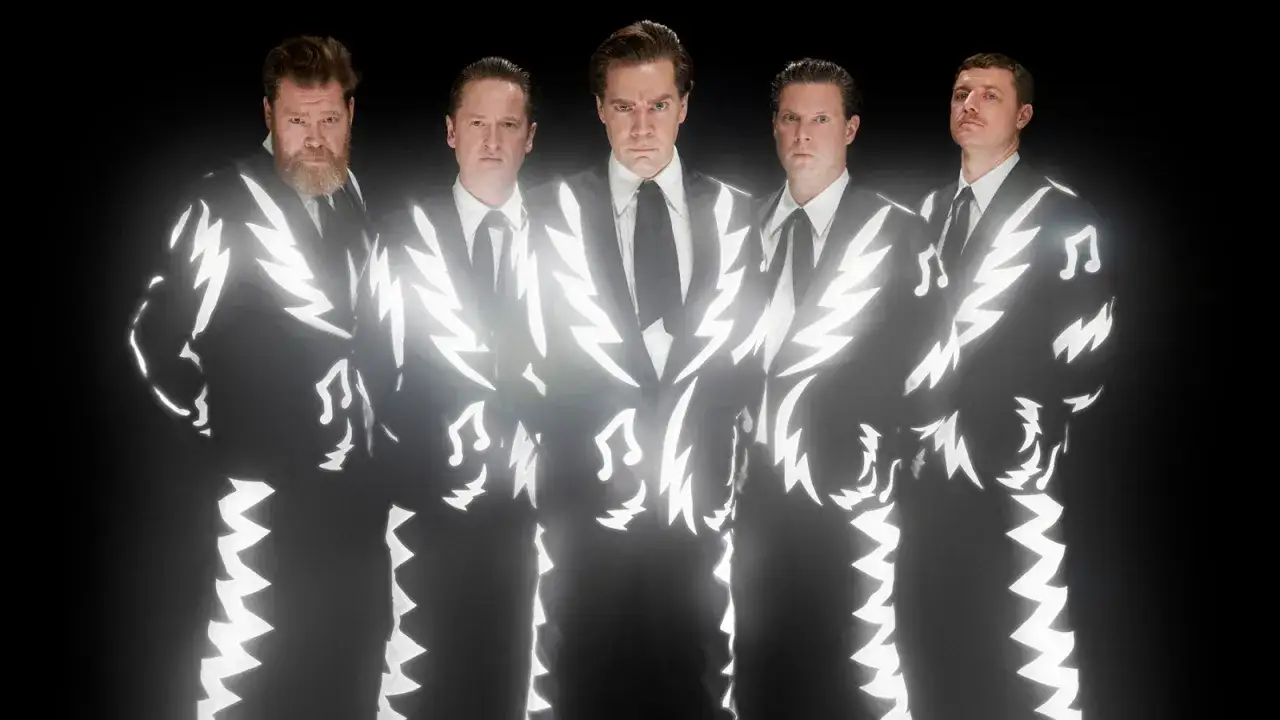 Los miembros de The Hives posan con trajes negros adornados con rel&aacute;mpagos blancos y notas musicales, listos para desatar su energ&iacute;a.